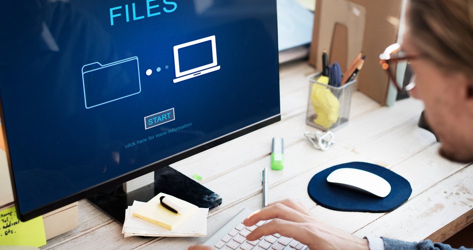 Person mit Brille sitzt vor Laptop, auf dessen Display sind Files, die hochgeladen werden mit Schaltfläche Start