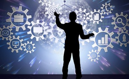 Mann steht vor einem Touch-Screen auf der eine Weltkugel und diverse digitale Zahnräder zu sehen sind, er berührt zwei davon